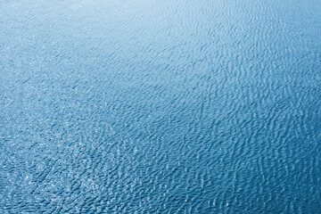 Tranquil blue water surface reflecting sunlight against soft ripples