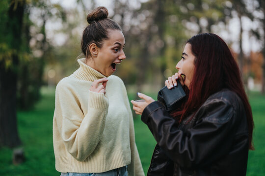A lively outdoor scene capturing two young women sharing an enthusiastic and exciting reaction.