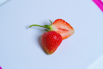 Eine geteilte Erdbeere liegt auf einem Brettchen auf dem Tisch