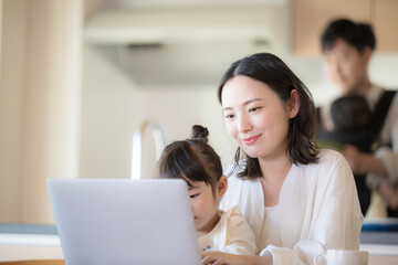 自宅のリビングで仕事をするママと家事をするパパ　リモートワーク、共働きや主夫のイメージのクローズアップ © kapinon