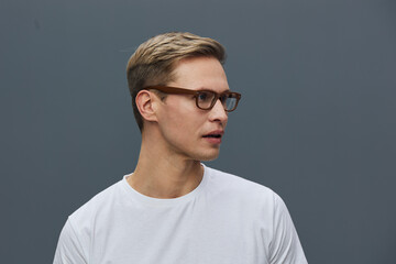 Fototapeta premium young caucasian man wear glasses white t-shirt look side isolated on gray background studio portrait remote work digital nomad concept