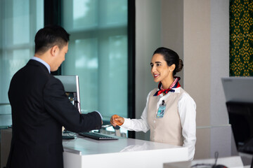 receptionist at desk in airport : Hispanic woman receptionist helping traveler with passport for...