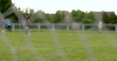 Children practicing soccer on a grass field, including goal net and players in motion, capturing the essence of youth sports and teamwork - Powered by Adobe
