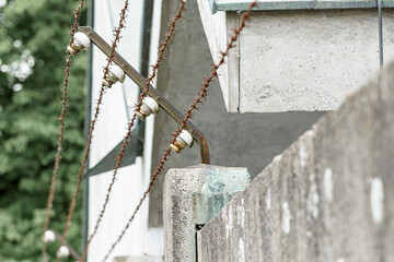 Barbed wire and electrical posts along a concrete wall in an urban environment during the day