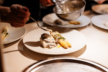 Chef en cuisine dressant les morilles sur le poisson et les asperges 
