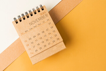 Blank desk calendar for November 2025 on brown tone background.