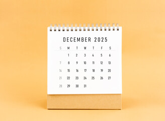December 2025 desk calendar on yellow background, Front view.