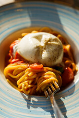Fork lifting spaghetti with burrata and tomato sauce