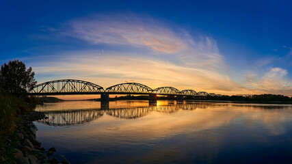 A large panoramic shot of the bridge over the river against the sunset background. An epic photo of the bridge