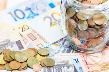 Coins in a glass jar on the background of other money. Belarus money