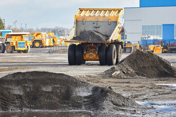 Yellow dump truck for open transportation of minerals works in a quarry