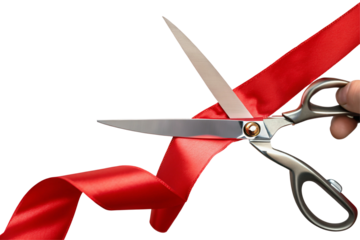A close up of scissors cutting a red ribbon held by a hand on a black background studio shot style