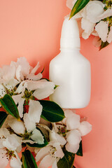 Nasal spray for allergies on a pink background. White flowers, space for text.