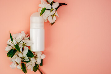 Deodorant bottles and flowers on pink background. Personal care product. Cleanliness and freshness