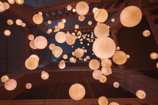A low-angle photograph captures a mesmerizing view looking up at a multitude of glowing, spherical paper lanterns.