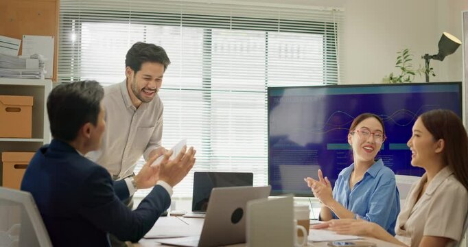 Asian business team claps and smiles while celebrating male colleague's achievement during office meeting. Workplace recognition, motivation, support, and positive team culture in action.