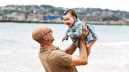 A grandfather lifted his granddaughter as they spent time at the beach