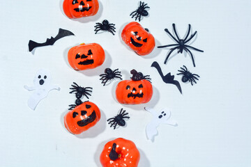 Halloween frame with party decorations of pumpkins, bats, ghosts, spiders on blue background from above. Happy halloween card in flat lay style.