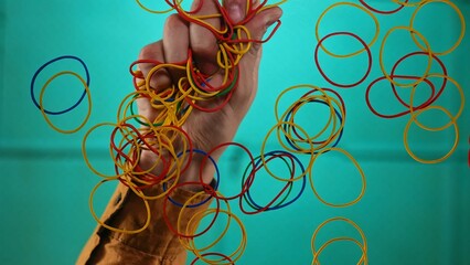 Hand Holding Colorful Elastic Bands Against Blue Background