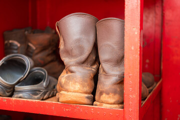 Leather safety boots with metal toe, PPE for construction worker which is keep on the rack shelf. Industrial safety equipment object, close-up and selective focus.