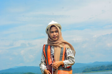 A female fish farm manager wears a safety vest and carries a book to check the work.