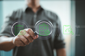Businessman holding magnifying glass inspecting digital checklist icons on transparent interface.