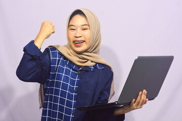 Portrait of a smart-faced Muslim female student wearing glasses, holding her laptop
