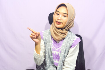 Young asian muslim woman standing with confidence, pointing gesture against purple isolated background