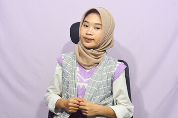 Young asian muslim woman standing with confidence, pointing gesture against purple isolated...