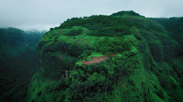 4K Aerial shot of Lush green landscape as seen from Savalya Ghat view point in Tamhini Ghat near Pune in Maharashtra, India. Rotating drone shot of Sahyadri hills during rainy day. Nature background