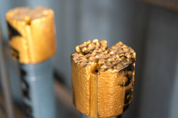 Drilling bit or milling head which insert carbine cutting in metallic gold color keep in shelf at workshop storage place. Industrial equipment object, close-up and selective focus.