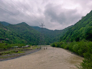 Green hills frame the winding river in Batumi, Adjara, Georgia. Gentle clouds hover over the...