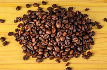 Coffee beans in a pile on rustic wooden surface – natural texture and aroma concept