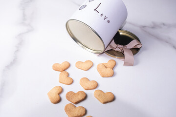 Heart shaped cookies next to a circular white box with a metal lid.