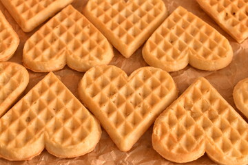Freshly baked heart waffles arranged on parchment paper. Sweet and simple breakfast or dessert with homely feel.