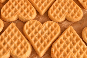 Heart-shaped Belgian waffles on baking parchment. Soft homemade treat with rustic and cozy breakfast vibe.


