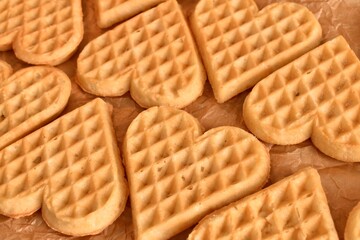 Freshly baked heart-shaped waffles on baking parchment. Homemade and sweet, ideal for a cozy or romantic breakfast.
