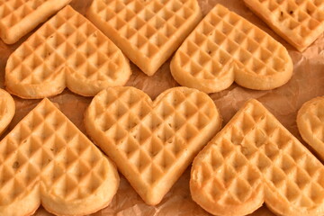 Freshly baked heart-shaped waffles on baking parchment. Homemade and sweet, ideal for a cozy or romantic breakfast.