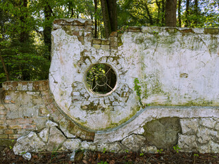 Framed by greenery, an old, weathered wall showcases circular architectural details. The structure stands as a testament to history, inviting exploration and reflection in Batumi, Adjara.