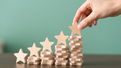 Hand placing wooden star on top of stacked blocks representing business growth