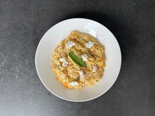Creamy Pumpkin Risotto with Goat Cheese and Fresh Sage on White Plate – Gourmet Autumn Meal