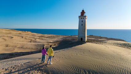 Couple explores the iconic lighthouse on the sandy shores of Denmark during a serene day