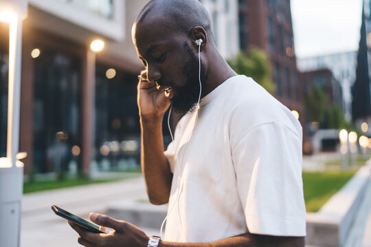 Young African-American man smiles while taking selfie with smartphone, capturing moment of self-representation, digital identity and mobile social presence in tech-driven era.