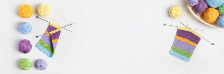 Yellow, green, blue, orange and lilac colors knitting balls in basket with knitting needles and knitted scarf on gray background. Set for the hobby of knitting warm clothes or toys. Concept needlework