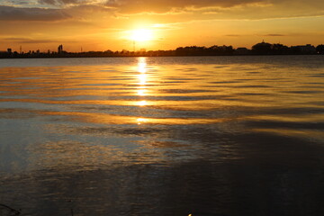 Golden sunlight reflects on tranquil river water under an expansive sky