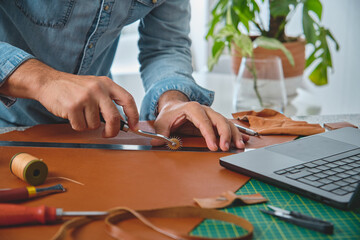 Craftsman using stitching groover and ruler to work leather in his workshop