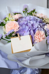 Delicate bouquet with hydrangea, lisianthus, and carnations in soft lavender and pink tones, wrapped in white paper — perfect for weddings, gifts, or romantic decor. empty card for writing