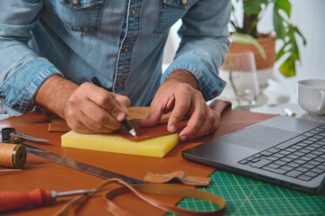 Craftsman meticulously marking leather for a new bag, showcasing traditional craftsmanship in a...