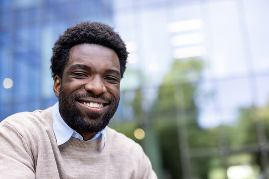 Fototapeta A cheerful black man with a warm smile is the focus of this image, taken outdoors with a modern backdrop. He looks happy.