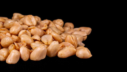 Close-up of a pile of roasted peeled peanuts on a black background. Perfect for culinary, snack, and food ingredient concepts.